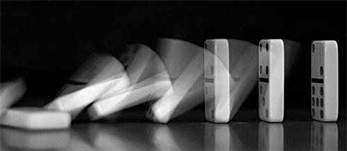 Dominoes falling in a chain reaction, captured with motion blur
