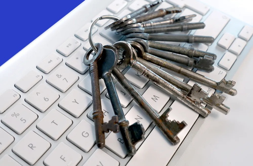 A bunch of old skeleton keys resting on a white computer keyboard