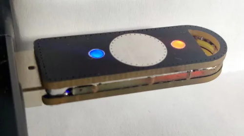 A homemade electronic device with a white circle, a blue light, and an orange light
