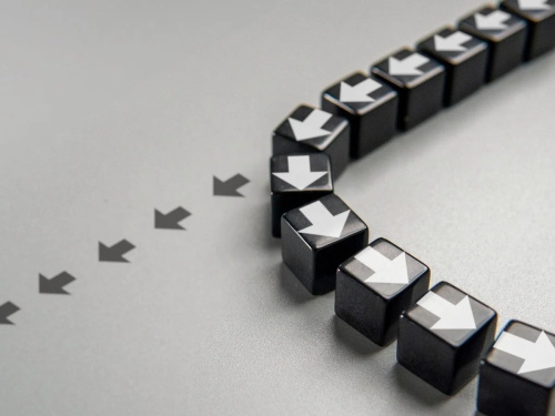 A curved path of black cubes with white arrows, with faint gray arrows leading to them
