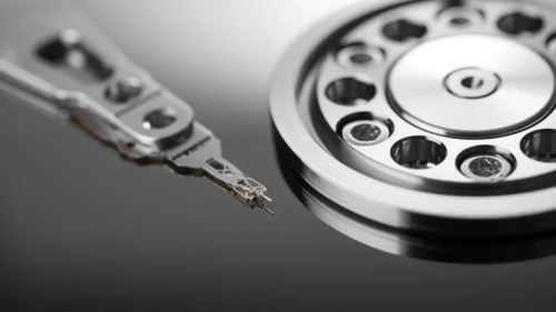 A close-up view of a hard disk drive's read/write arm next to the platter