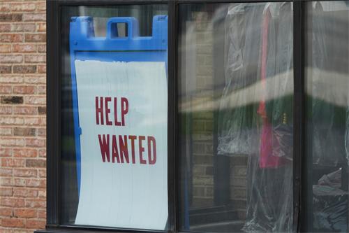A "HELP WANTED" sign posted in a storefront window