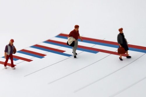 Miniature figures walking on a red-and-blue bar chart