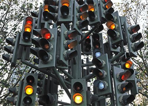 A chaotic cluster of traffic lights, many showing yellow or red signals