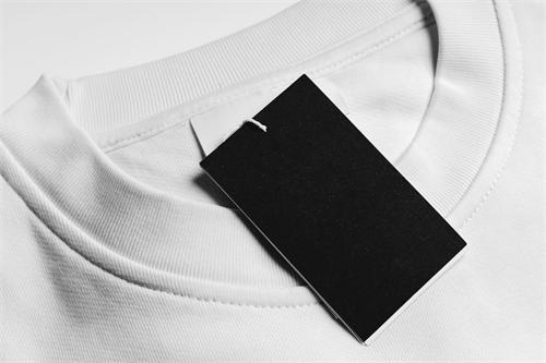 A blank black clothing tag attached to the collar of a white t-shirt