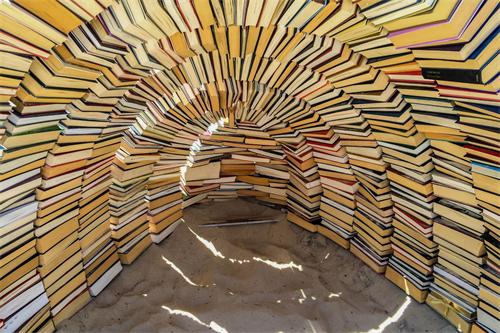 A spiral, tunnel-like structure built from stacked books, forming a circular enclosure